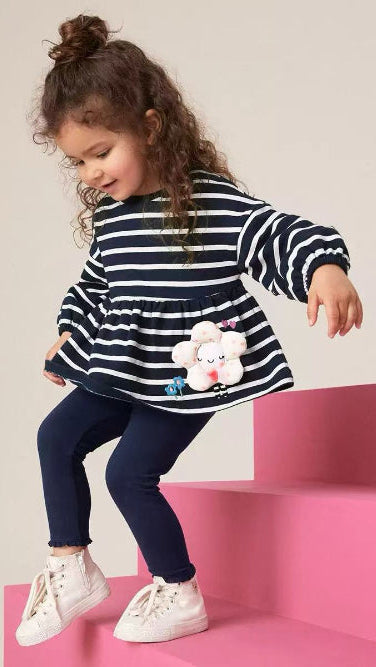 Child wearing a striped sweater and navy pants on a pink and beige background